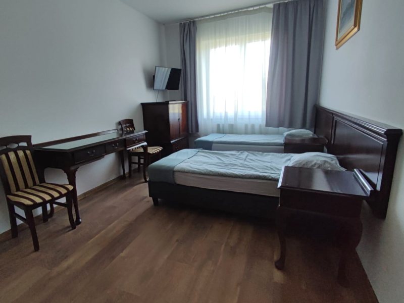Pokój dwuosobowy w Baltic Resort z dwoma łóżkami, biurkiem, krzesłami i telewizorem