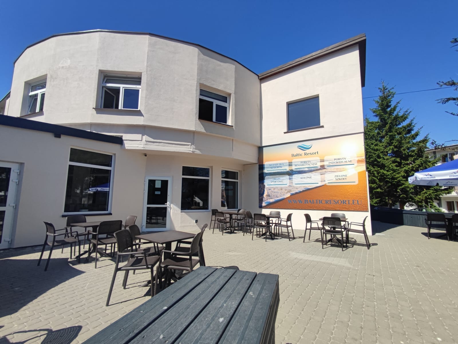 Budynek ośrodka Baltic Resort z tarasem, stolikami i parasolami