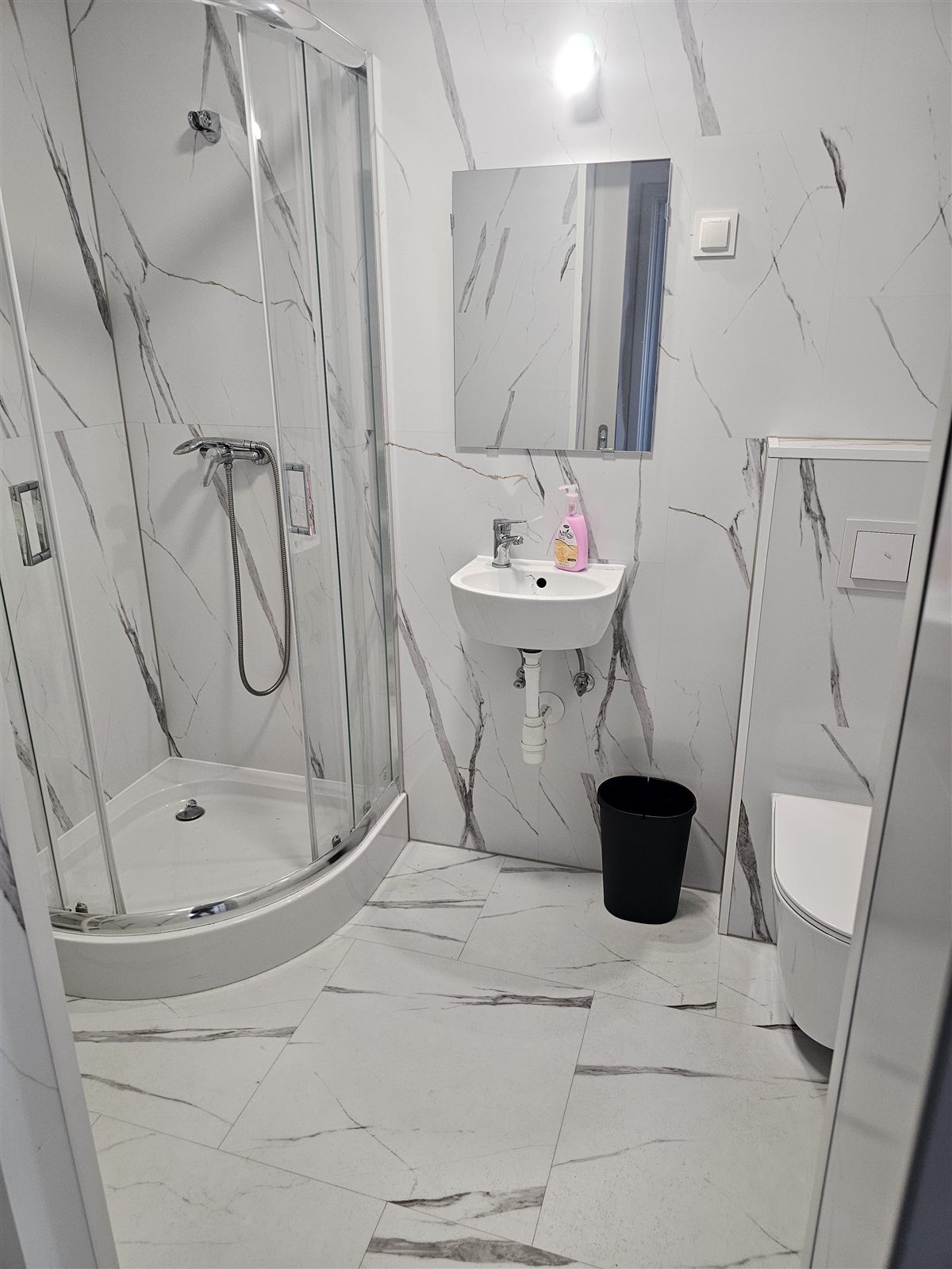Łazienka przy pokoju w Baltic Resort z kabiną prysznicową, umywalką i jasnymi płytkami w marmurowy wzór