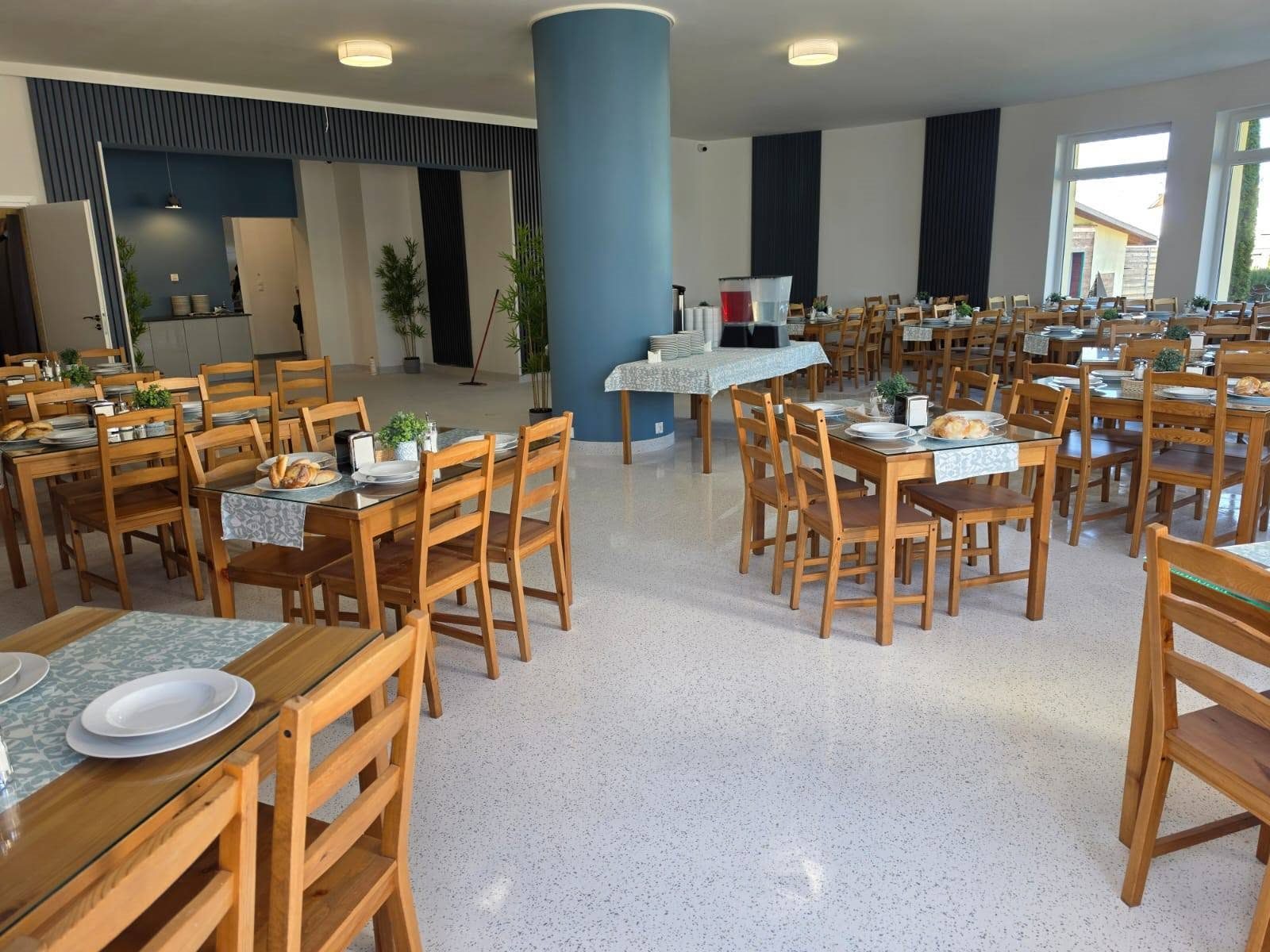 Przestronna stołówka Baltic Resort z drewnianymi stołami nakrytymi do posiłku i bufetem z napojami